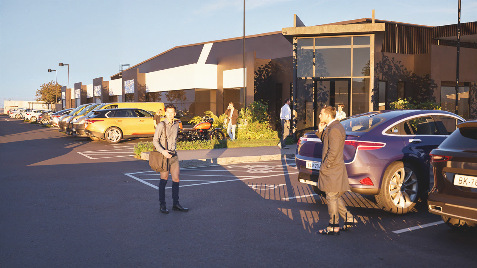 The refurbished office frontage at golden hour with staff arriving across the car park