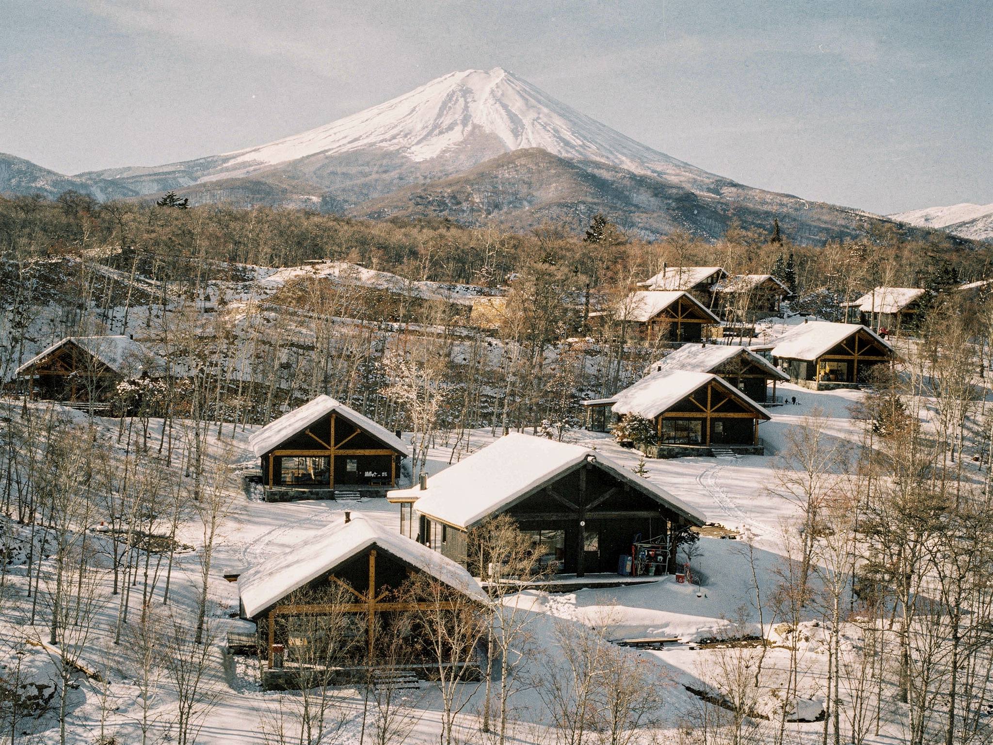 Aerial view of the lodge collection scattered through the Niseko birch forest, Mt Yōtei beyond on a clear morning