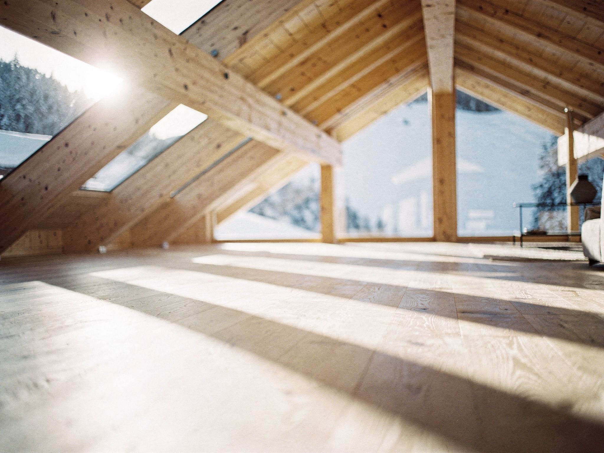 Morning light raking through the glulam trusses onto an oak floor