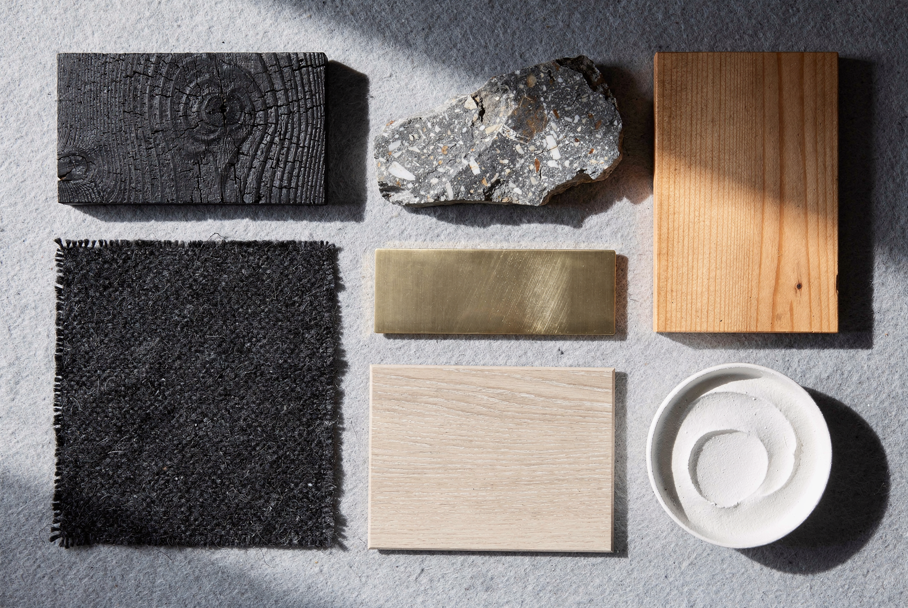 Material board photograph — charred cedar, stone, fir, wool, brass and oak