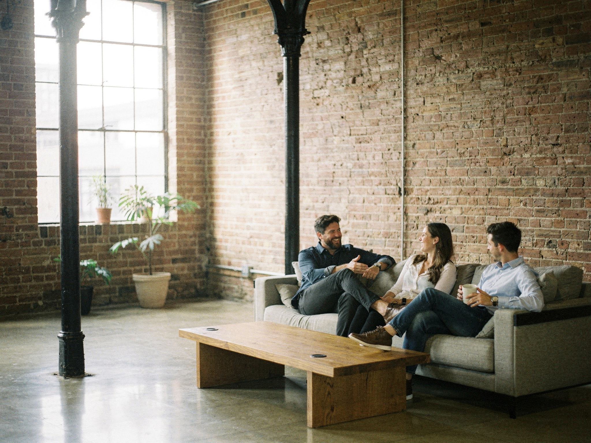 Colleagues talking on low sofas in a brick breakout lounge
