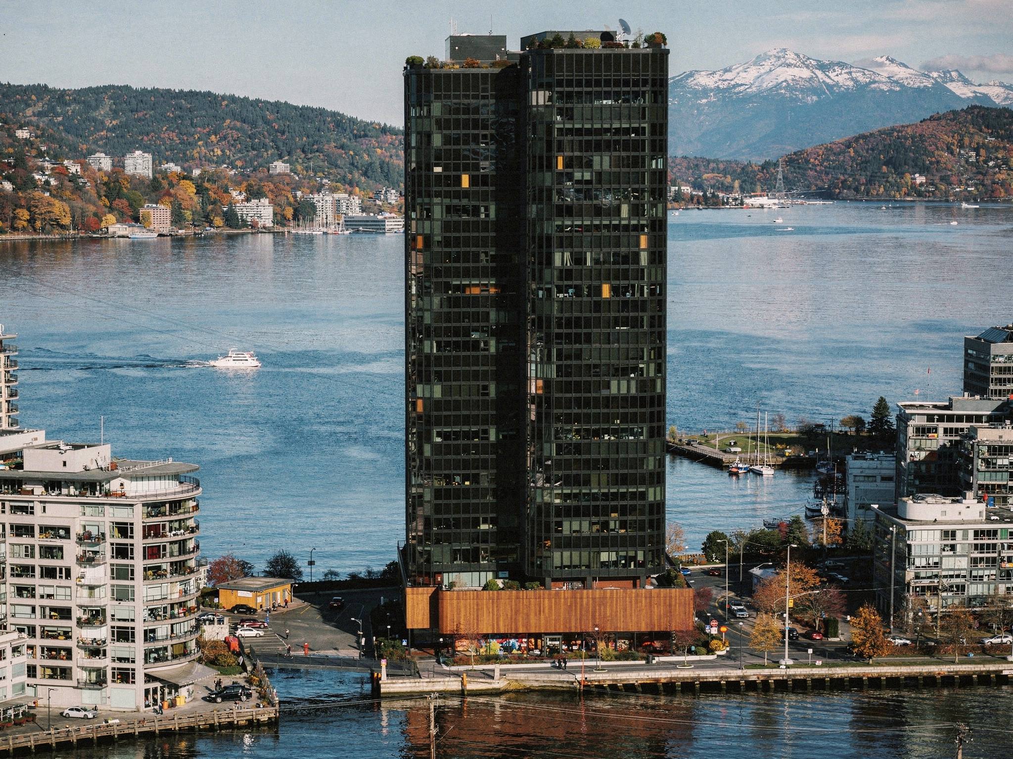Aerial view over Burrard Inlet toward the black-glass tower on the Coal Harbour waterfront