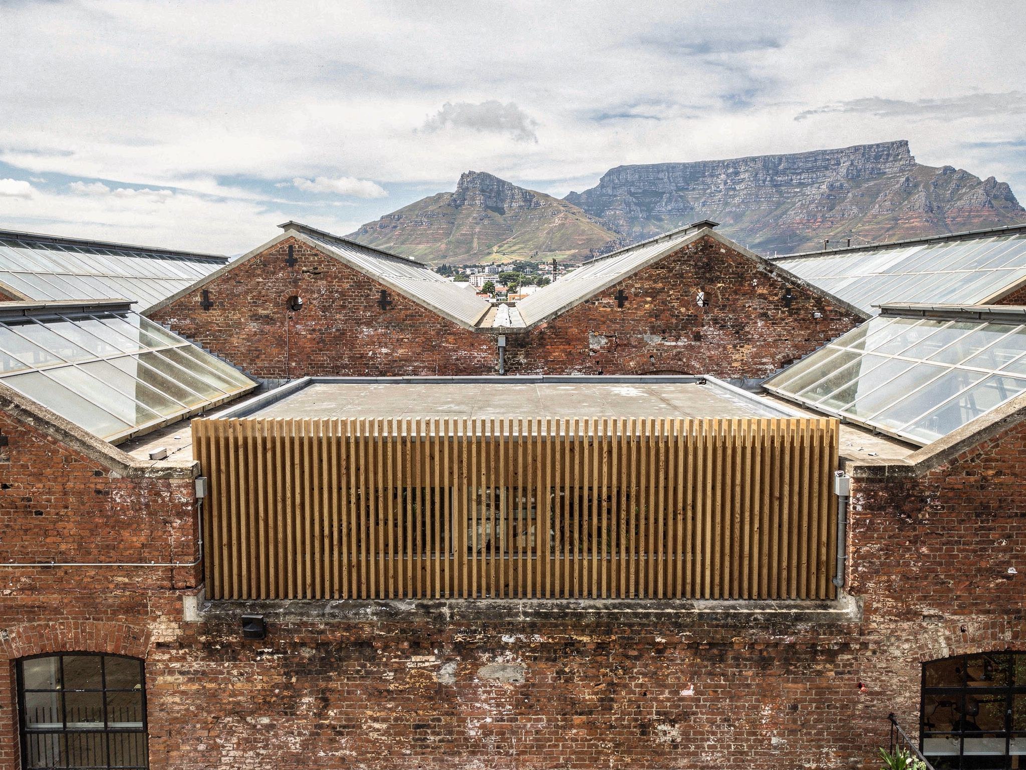 Aerial visualisation of the sawtooth brick roofs with new glazed rooflights and Table Mountain behind