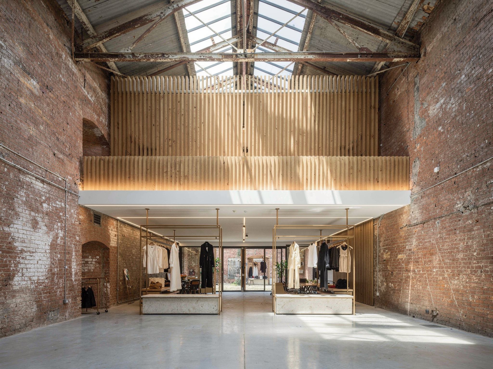 High-end fashion tenancy with steel rails and travertine plinths standing clear of the brick wall