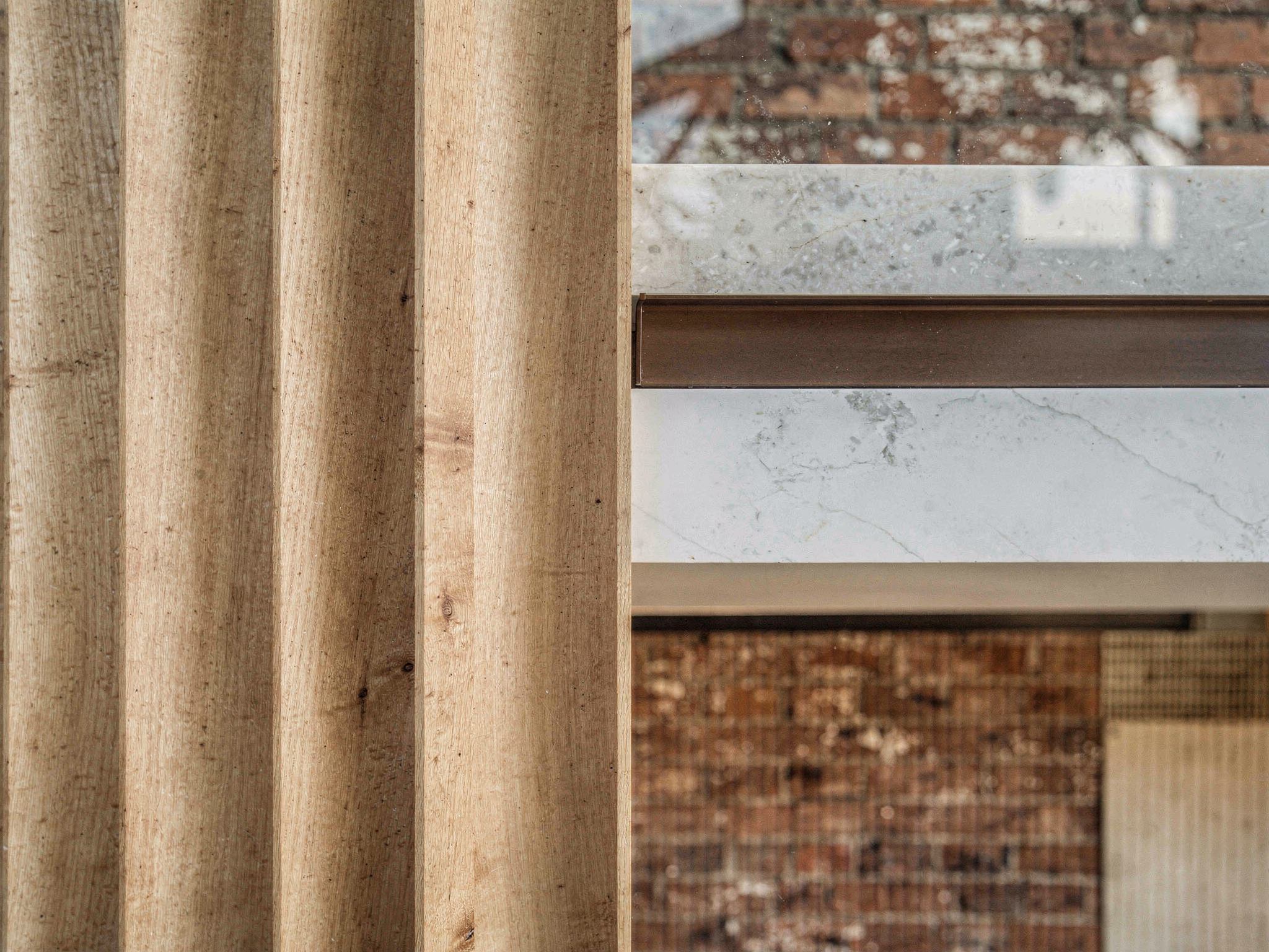 Close crop of brick, terrazzo, blackened steel, oak and brass together